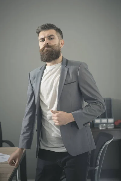 Γενειοφόρος άνδρας με casual κοστούμι στο γραφείο. Άνδρας με γενειάδα και το μουστάκι στο σοβαρό πρόσωπό. Αυτοπεποίθηση επιχειρηματία στο χώρο εργασίας. Γραφείο και επιχειρηματικό τρόπο ζωής. Αυτοπεποίθηση και επιτυχία έννοια — Φωτογραφία Αρχείου