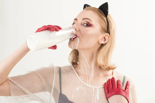 Young cat woman drink milk from glass bottle.