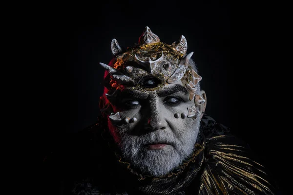 Man with dragon skin and white beard. Blind monster with three eyes and sharp thorns on his face. Demon head on black background, supernatural concept