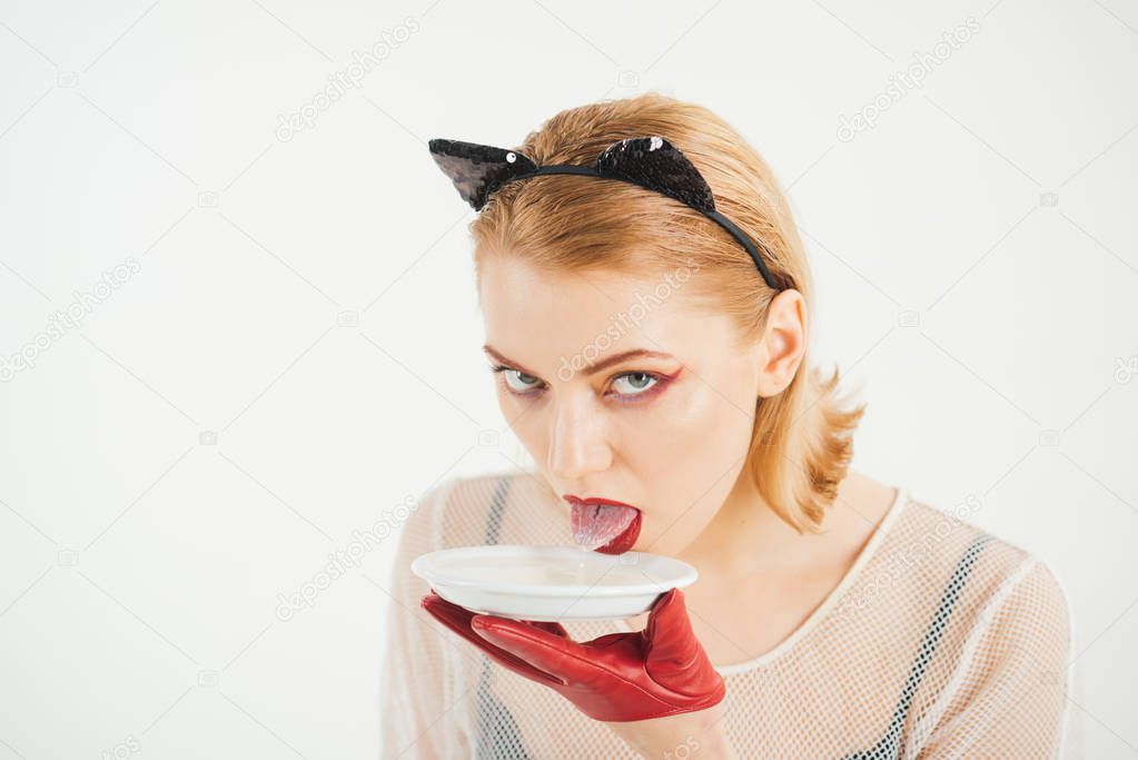 Sexy cat woman lick milk from plate. Food and drink. Dieting and health. Ecology product and heath. Cat woman eat sour cream. Girl in kitten ears and red gloves with yoghurt isolated on white.