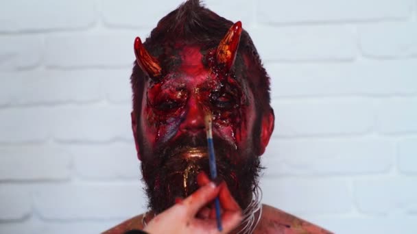 Halloween. Mooie man met heldere halloween make-up. Halloween Make-Up. Portret van een jonge man met bang halloween make-up. Halloween Make-up van de toepassing van de Visagist. — Stockvideo