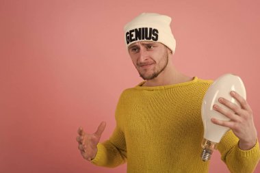 brilliant idea. Genius idea. Portrait of young man having idea over pink background. Guy in hat holds lamp in hand. Idea concept clipart