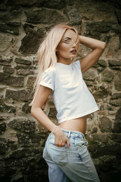 Estilo jeans. Mulher loira sexy vestindo jeans, posando na parede. Estilo de juventude — Fotografia de Stock