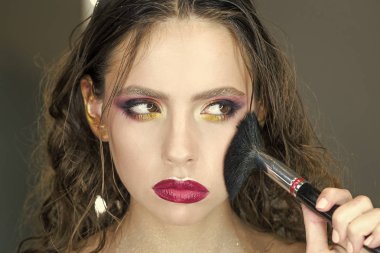 Güzel yüz ve makyaj. Mükemmel cilt. Makyaj uygulamak. Güzellik kız makyaj fırça ile. Kahverengi gözlü esmer kadın için parlak tatil makyaj. Güzel yüz ve makyaj. Mükemmel cilt