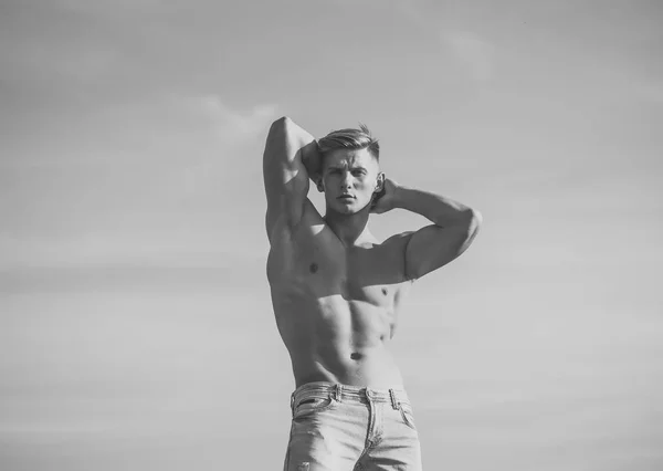 Istruttore di fitness. Macho mostra busto muscolare in jeans sul cielo blu — Foto Stock