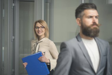 Mutlu kadın ön planda bulanık adamla. İş kadını bardaklarda dosya klasörü tutun. Seksi Sekreter office belgeleri ile gülümse. Evrak ve bürokrasi kavramı. Yoğun bir gün ofiste