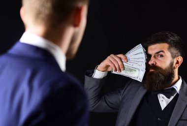 İşadamı avuç dolar tutar. Satınalma kavramı. Resmi elbiseli adamlar iş anlaşması için buluş. Adam ile nakit para ödüyor. İşadamları, siyah arka plan arasında finansal anlaşma
