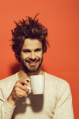 sabah ferahlık ve içki, enerji. çay veya kahve iç çamaşırı kırmızı zemin üzerine uncombed saçlı mutlu adam.