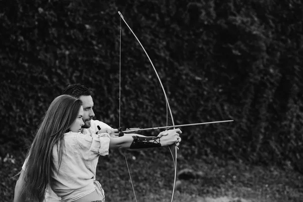 Concentrate and aiming. man and pretty woman shooting with bow and arrow — Stock Photo, Image