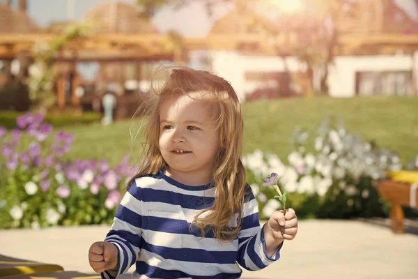 Sevimli küçük çocuk çayır yeşil çim ile poz. Suratının ortasına mavi ve beyaz çizgili gömlek gülümseyen çocuk çocuk