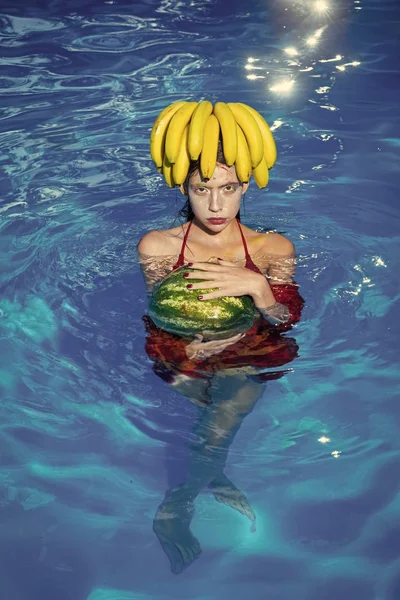 Fille avec des fruits dans la piscine. fille avec des fruits tropicaux dans la piscine. fille nager avec pastèque et banane dans l'eau — Photo