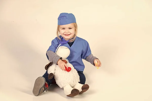 child heals toys. doctor kid in uniform playing vet with toy animal