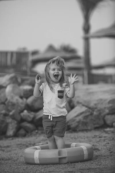 Baby care a dětství koncept. Malé dítě směje v kruhu oranžová život na pláži. — Stock fotografie
