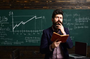 Modern öğretmen hippi matematik formülü ile büyük yazı tahtası üzerinde yazılı. Kitaplığındaki kitap okuyan üniversite öğrencileri. Güzel öğretmen öğrenci ilköğretim okulunda sınıfta yardım