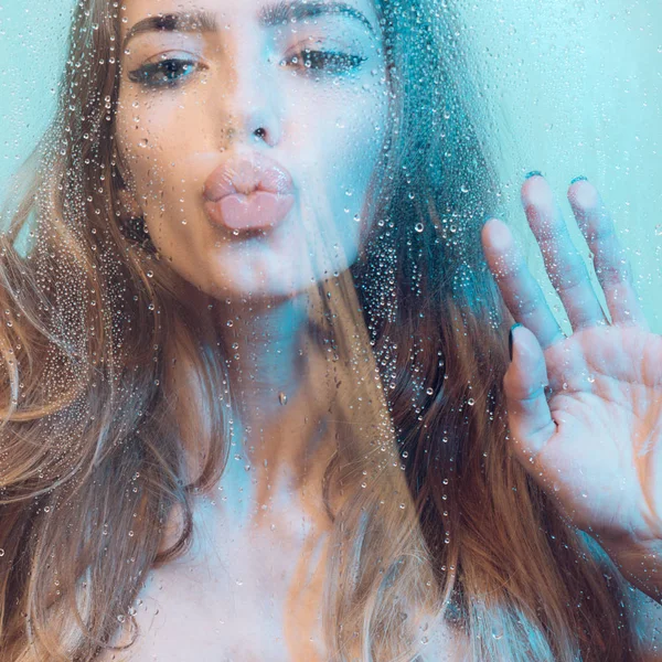 Donna sexy sotto la doccia. Attraente giovane donna nuda sotto gocce d'acqua su sfondo blu — Foto Stock