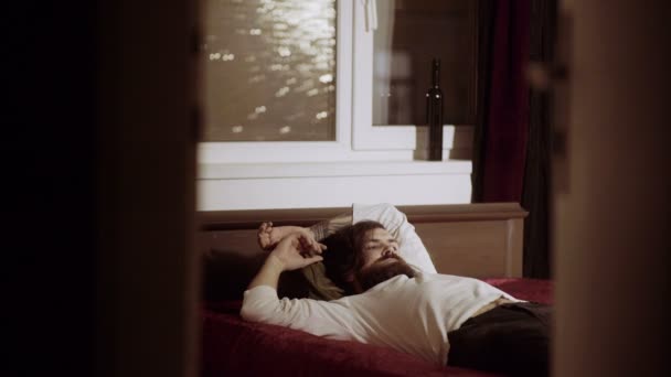 Κουρασμένος άνθρωπος αναπαύεται σε κρεβάτι σε δωμάτιο — Αρχείο Βίντεο