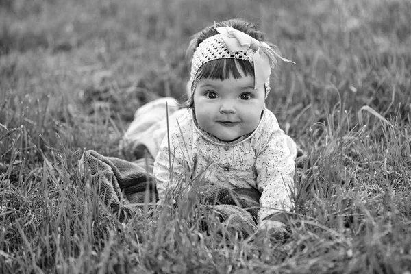 Child lies on the grass and smiles. Cute baby girl on green grass — Stock Photo, Image