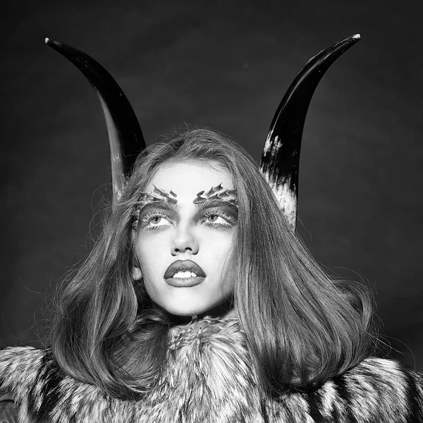 Woman with make-up in the style of a demon. Girl with antlers and fur coat — Stock Photo, Image