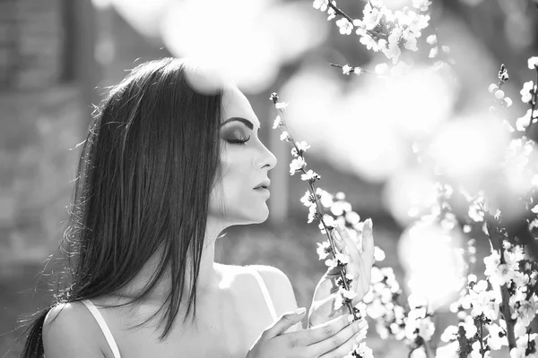 A rapariga está a cheirar flores. Mulher com flor de primavera — Fotografia de Stock