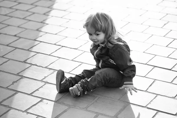 Kind zit op het asfalt. Kleine jongen zit op de stoep — Stockfoto
