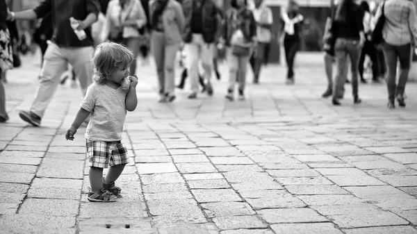 人々 の広場の真ん中に少年。お団子を食べる男の子 — ストック写真