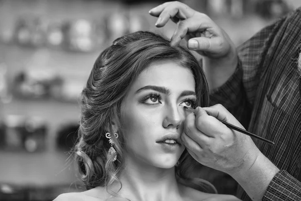 El hombre está poniendo rímel en las pestañas. Mujer joven con hermoso maquillaje — Foto de Stock