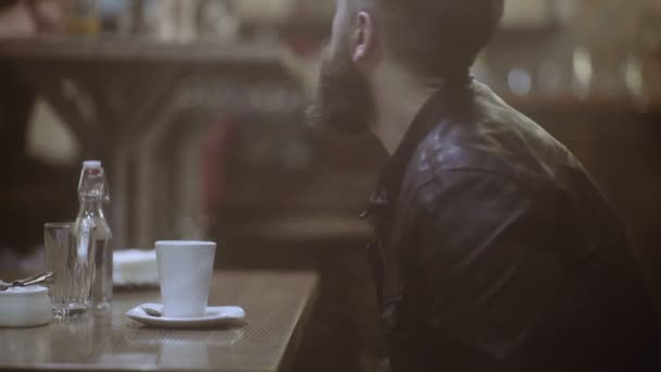 The young man has coffee and looks out of the window. Portrait of the handsome man. — Stock Video