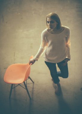 umutsuz ya da yalnız ve depresyonda hissediyor. düşünceli kadın evde portakal sandalye ile. tembel gün evde. Sinir bozucu kadın ayakta ve dış saha yukarı bakıyor. ev konfor kız sandalye ile.
