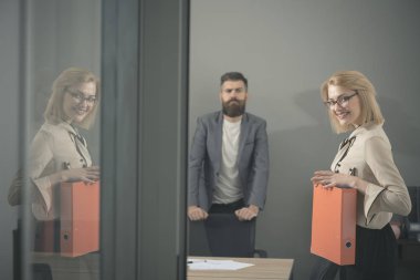 İş kadını elinde raporlarla kameraya bakıyor.