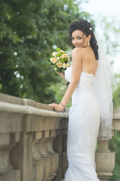 Elegante novia sonriente fresca en vestido blanco con ramo de flores — Foto de Stock