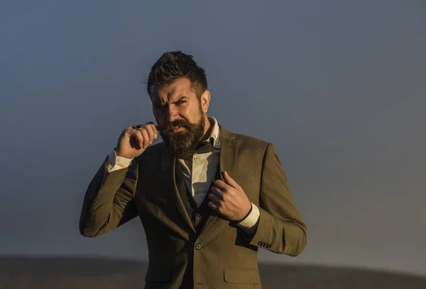 Homem bonito hipster ou cara com barba e bigode no rosto sério ao ar livre no topo da montanha contra o céu nublado no fundo natural, espaço de cópia — Fotografia de Stock