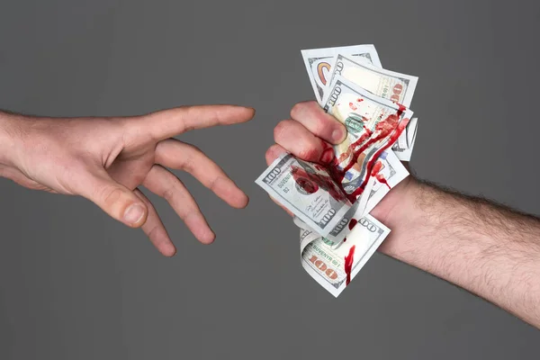 Il dito sanguinante ferito alla mano tiene sfondo grigio banconota dollaro. Concetto di denaro sporco. Dannata moneta. Consegnare profitti criminali. Dollaro segnato da omicidio. Denaro coperto da tracce di reato — Foto Stock