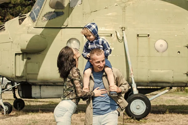 Conceito de desenvolvimento e educação. Mãe e pai e seu filho andando no museu da aviação ao ar livre. Feliz família passar o tempo juntos, em excursão, helicóptero ou avião em segundo plano, dia ensolarado — Fotografia de Stock