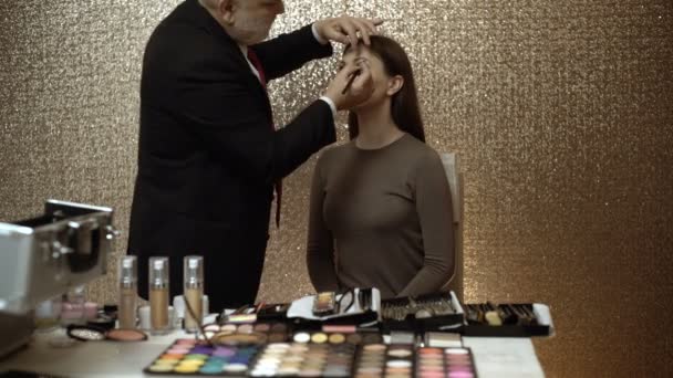 Artista de maquillaje profesional mostrando clases magistrales de maquillaje. Artista de maquillaje profesional trabajando con una hermosa mujer joven — Vídeos de Stock