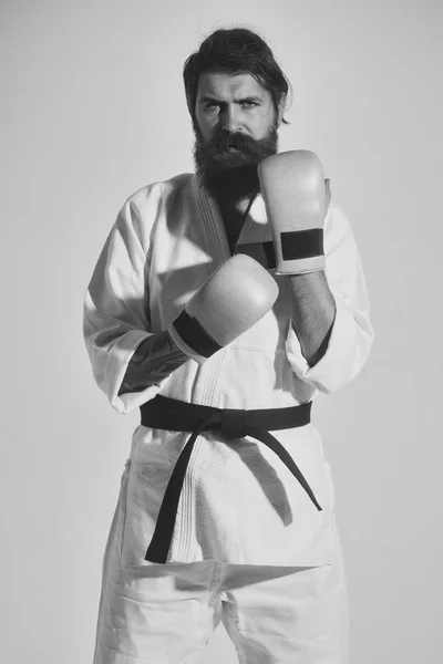martial arts. bearded serious karate man in kimono and boxing gloves