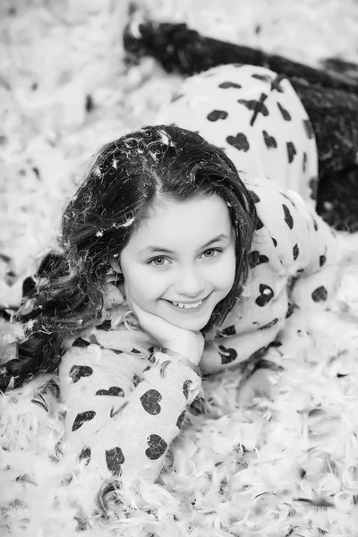 Fiesta de pijamas. Linda chica feliz en el piso cubierto con plumón y pluma —  Fotos de Stock
