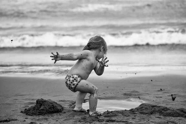 El niño está de vacaciones en el mar. Lindo niño fangoso juega con arena mojada — Foto de Stock