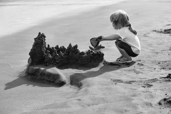 Descansar en el resort. Lindo bebé niño construye castillo de arena en la playa del mar — Foto de Stock