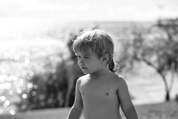 海のビーチに子供。ブロンドの髪のポニーテールでかわいい男の子が屋外 sunbathes, します。 — ストック写真