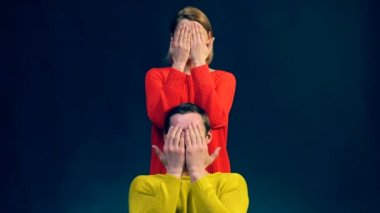 Bir kız kırmızı ve sarı kazak, ellerini sarılma bir çocuk bir siyah arka plan üzerinde farklı duygular göster. Duygular. Surprisment. Mutluluk. Şok. Üzüntü