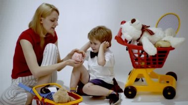 Anne ve oğlu alışveriş yapıyor. Anne oğluna para saymayı öğretiyor. Gülümseyen küçük çocuk annesiyle oyun oynuyor..
