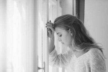 Kız pencerede üzücü. Güzel kız pencerede ayakta