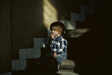 Çocuk inişte sıkılmış. Düşünme yüz çocukla oturup evi merdivende