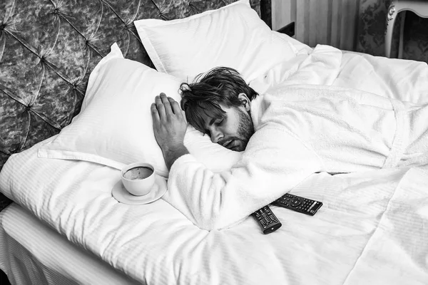 Otel Servisi. sakallı adam yatakta uzaktan kumandalı — Stok fotoğraf