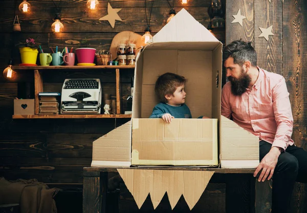 Concepto de lanzamiento de cohetes. Niño feliz sentarse en la mano hizo cohete. Niño lindo niño jugar cosmonauta o astronauta. feliz juego familiar con cohete hecho de caja de cartón —  Fotos de Stock