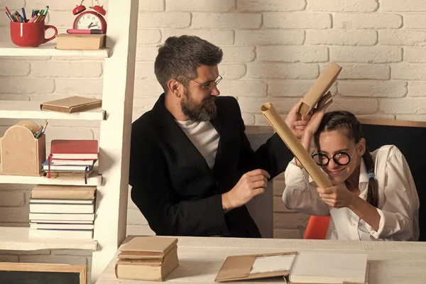 Hausaufgabenbetreuung. Mädchen mit Brille und bärtiger Mann kämpfen mit Schriftrollen — Stockfoto