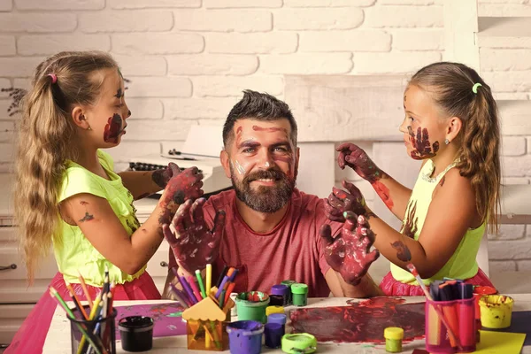 children draw a dad. Girls drawing on man face skin with colorful paints