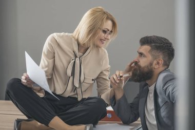 Başarılı işkadını yaratıcı saç kesimi ve onun yanında modern ofisinde oturan adam belgeleri teslim ederken mutlu gülümseyerek gözlük