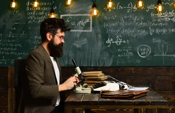 Mikroskop ile bilim adamı çalışın. Sakal ve bıyık okulda olan adam. Sakallı adam kara tahta araştırma yapmak. Gözlük ve optik aletleri masa ile iş adamı. Bilim ve eğitim
