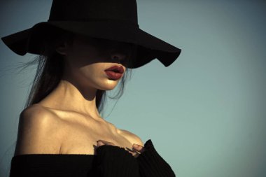 moda şapkalı bir kadın. kız mavi gökyüzü arka plan üzerinde kırmızı dudaklı. kopya alanı şık siyah şapkalı kız.